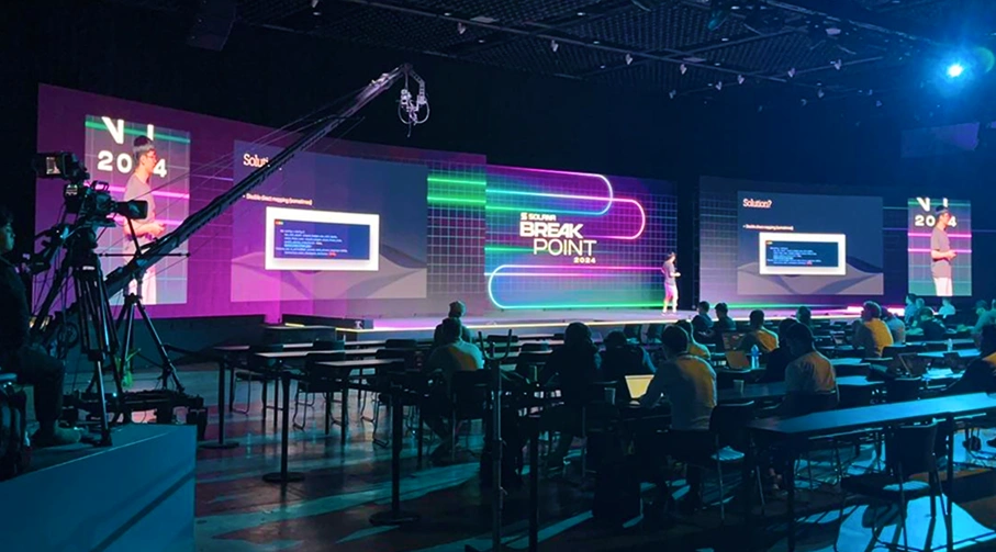 Large tech conference and seminar stage setup with LED video screens and broadcast cameras in Singapore