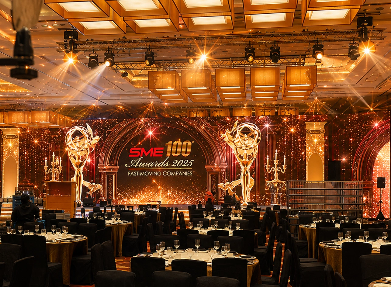 SME 100 Awards corporate gala dinner setup in Singapore grand ballroom featuring warm ambient stage lighting, overhead truss rigs, and custom LED backdrop
