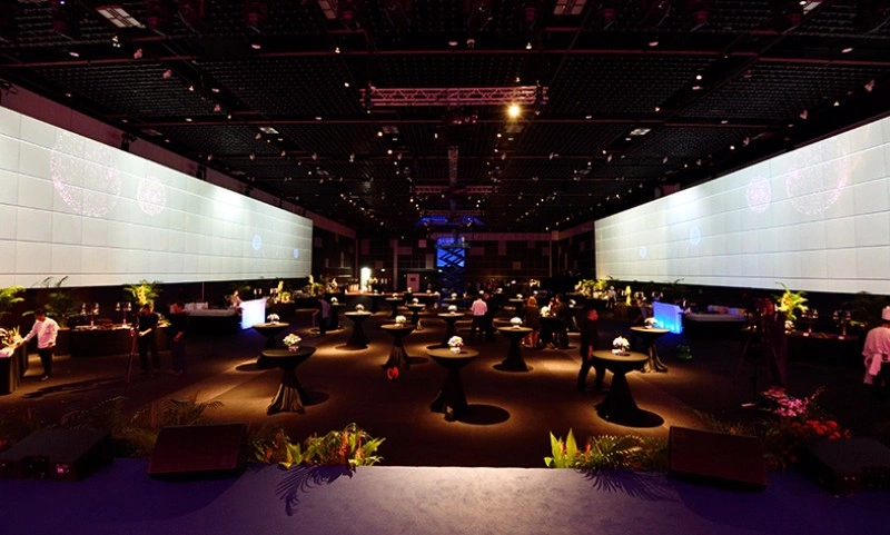 Large event hall with immersive widescreen projection panels and cocktail standing tables
